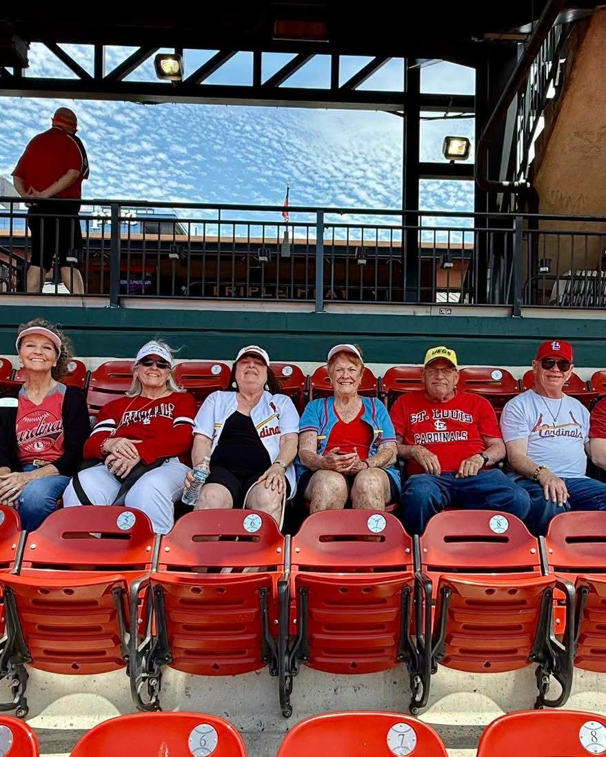 Six Autumn Ridge residents in Cardinals gear seated together at a baseball stadium