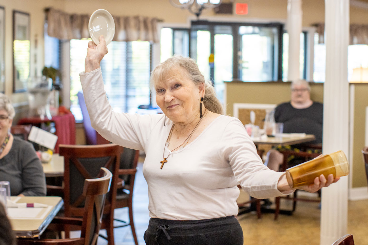 An Autumn Ridge resident dancing in the dining room, a plate raised in one hand