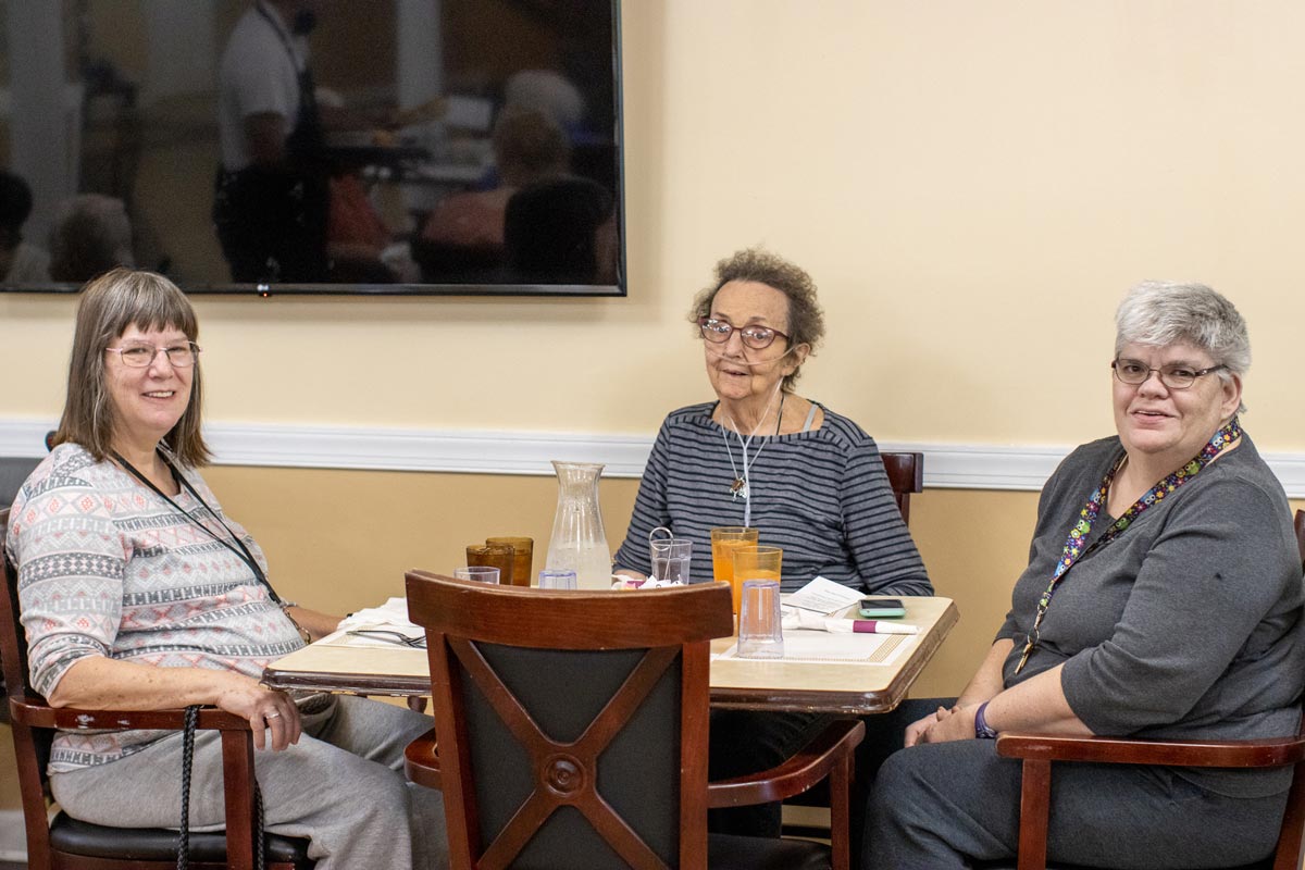 Three Autumn Ridge residents talking around a table in the dining room